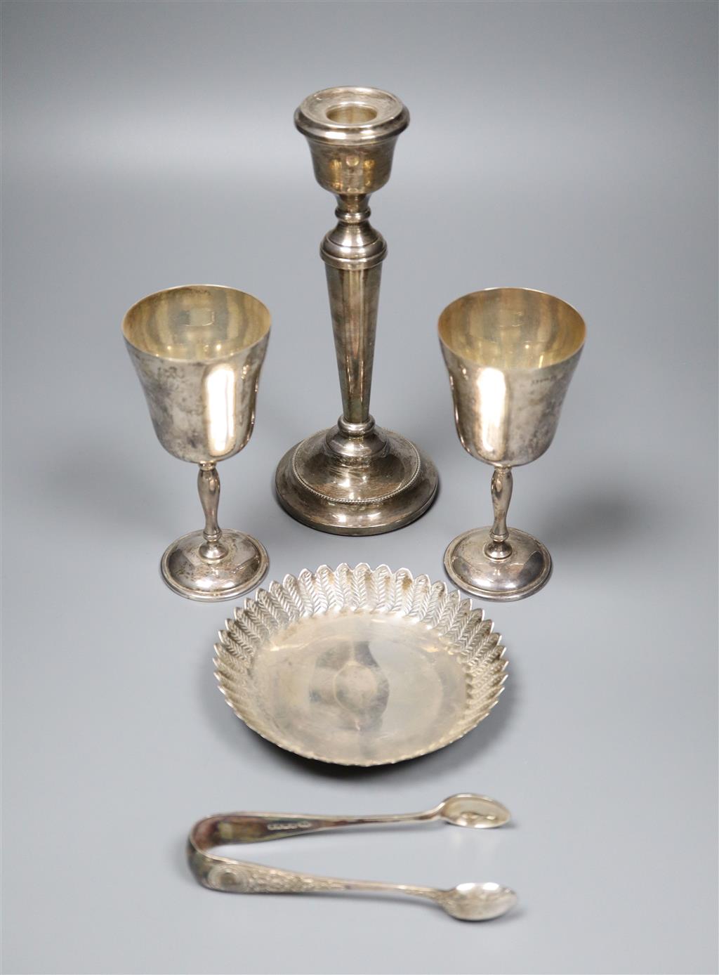 A pair of modern silver goblets, a silver candlestick, modern silver dis and pair of silver sugar tongs,